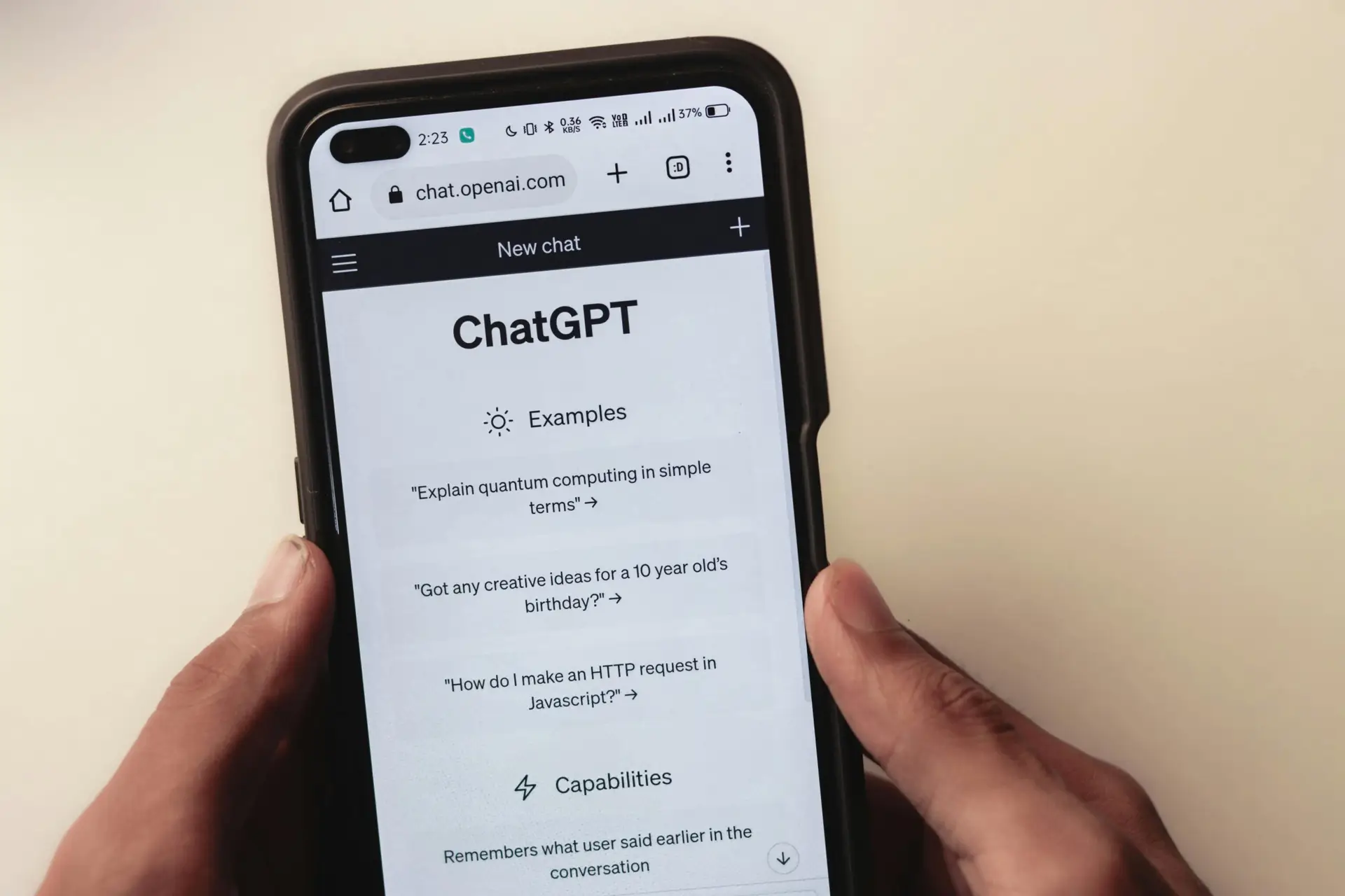 Close-up of hands holding a smartphone displaying the ChatGPT application interface on the screen.